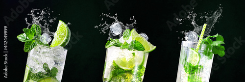 Glasses of Mojito with splashes and flying ice cubes on black and green background in bar | Limes, water, drops