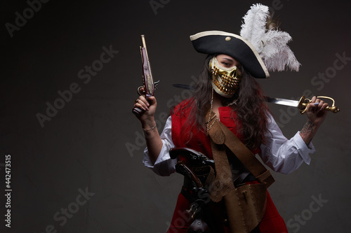 Tattooed female pirate posing with cutlass and gun