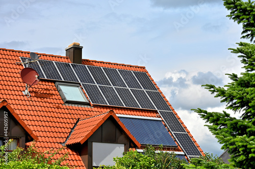 Nutzung der Sonnenenergie auf rotem Hausdach - Strom- und Warmwassererzeugung