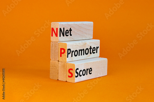 NPS net promoter score symbol. Wooden blocks with words 'NPS net promoter score'. Beautiful orange background. Business and NPS net promoter score concept. Copy space.