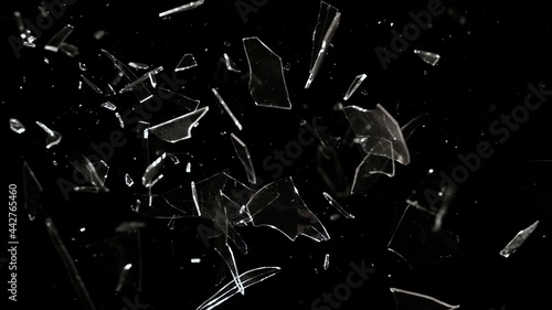 Studio full-frame wide plate shot of window glass pane shattering and breaking on black background. Real smash explosion at high speed as action concept template and overlay element.