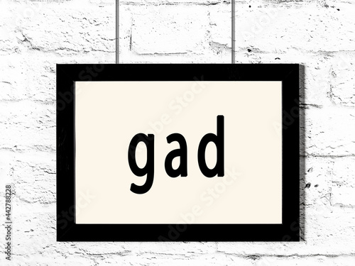 Black frame hanging on white brick wall with inscription gad