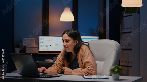 Happy cheerful businesswoman smiling while looking at laptop computer display receving winning corporate job promotion. newa Joyful happy executive manager working in company office late at night