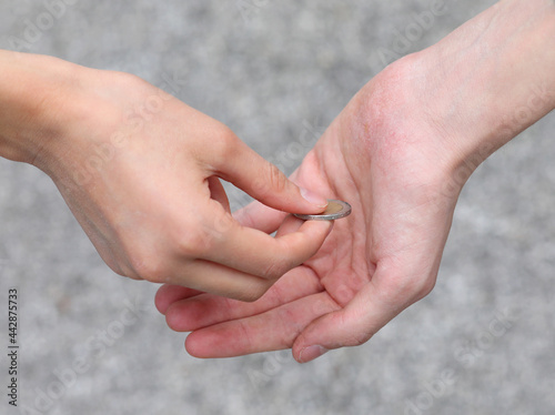 two hands a coin while giving alms