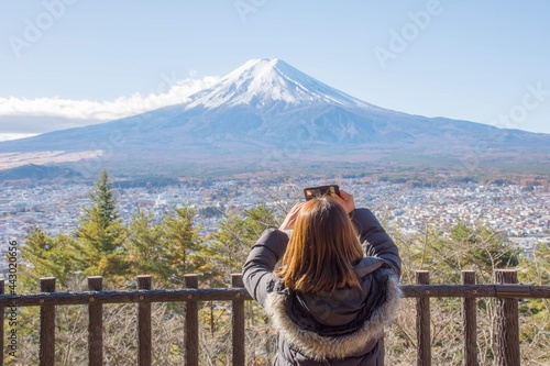 The unidentified tourist lady is Taking photo of Fuj San and city in high view with night blue clear sky take from Chureito Pagoda, Shimoyoshida station; near Kawaguchiko