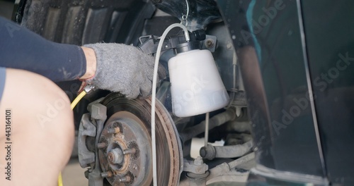 Auto mechanic replacing brake fluid on a vehicle, technician bleed air out of disc brake system in garage workshop, Car repair in a car service