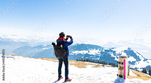 Happy time with young tourist blogger taking photo by smartphone with snow mountain at Switzerland with blue sky background