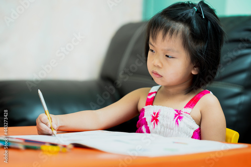 Asian child is sluggish having sleepiness while doing homework. Girl close half eyes. Cute kid aged 4-5 years old.