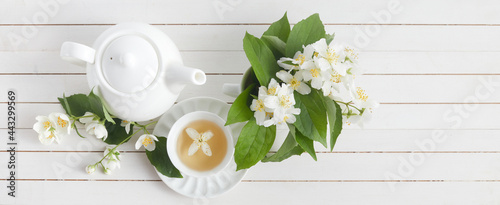 Jasmine flowers and teapot on white wooden background. Herbal tea of jasmine flower. Flat lay.