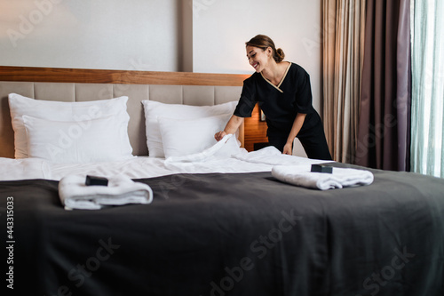 Attractive young maid tidying the hotel room.