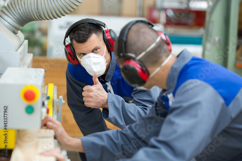 supervisor wearing dust mask giving thumbs up to worker