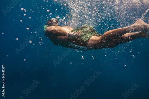 Man swimming underwater into the ocean
