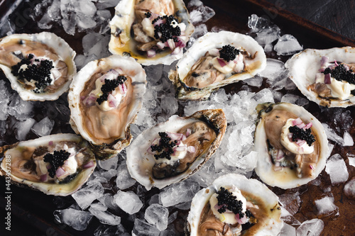 Dirty Oysters Served on a Bed of Crushed Ice: Raw oysters topped with caviar, minced shallot, and creme fraiche