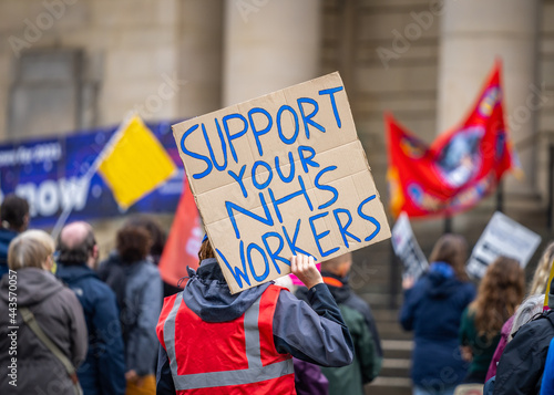 Support your NHS workers at protest rally holding home made placard sign to gain support for NHS key worker staff on march.