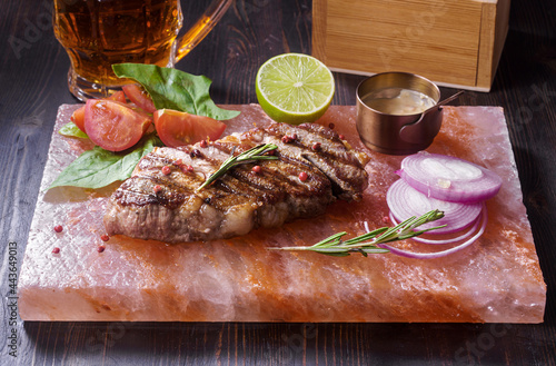 Grilled pork steak with rosemary, vegetables and lime served on himalayan salt tile