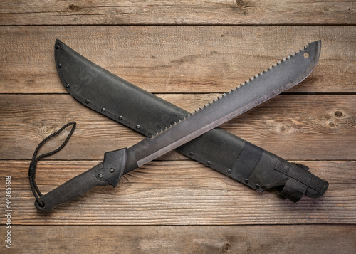 bush clearing machete with carbon steel blade and saw against rustic wooden deck