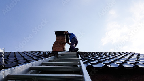 a chimney sweep climbs a metal ladder to the roof of the bathhouse to clean the pipe from burning