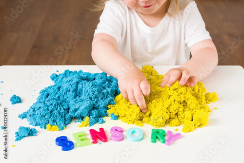 Little girl playing with magic kinetic sand, Sensory word. Early sensory education. Kidd's sensory experiences, games for fine motor skills. Therapy hand, development of fine motor