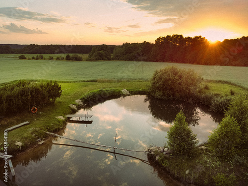 Sunset in the fields, cloud reflections in the pond, small oasis,