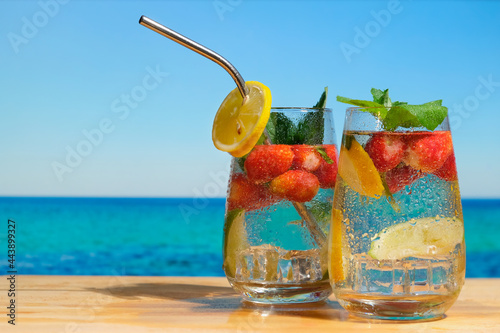Hard seltzer cocktails. Chilled drinks, beautiful summer beach on background. Summer cocktails, beach bar concept. 