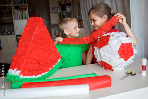 Kids doing pinata with cardboard from used box and color crepe paper, decorated container filled with candy as a part of celebration, diy decoration at birthday party, focus on boy
