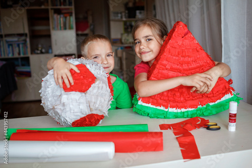 Kids hug pinata made with cardboard from used box and color crepe paper, decorated container filled with candy as a part of celebration, diy decoration at birthday party