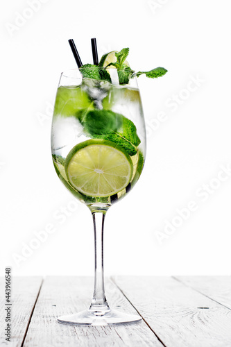 Cocktail in wine glass made with champagne, soda, lime, mint on white background.