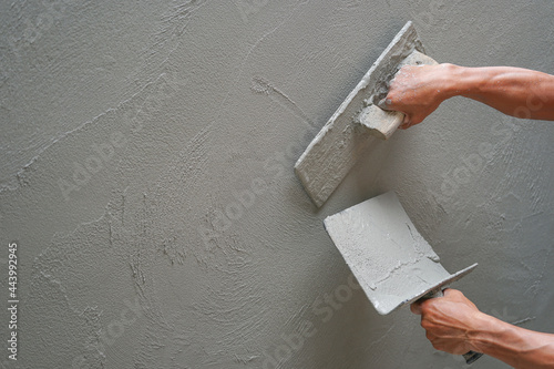 hand of worker plastering cement wall at construction site with copy space, selective focus