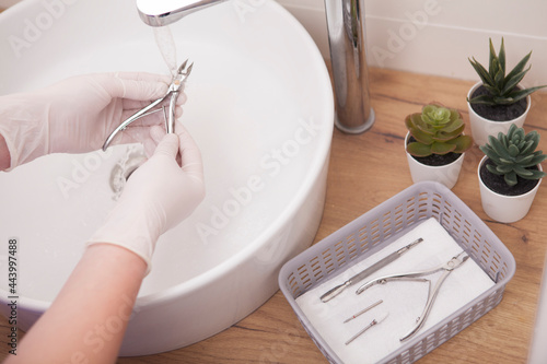 Cropped close up of manicurist cleaning nail nippers after sterilization