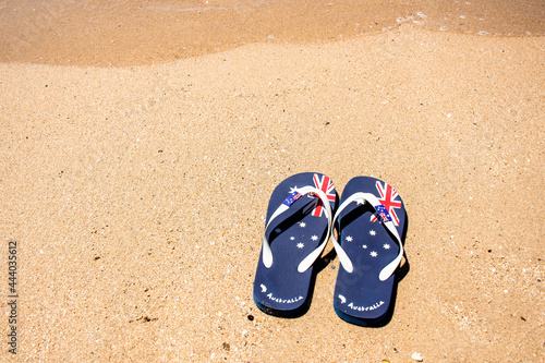 Australia Day and travel destination background:. Aussie thongs featuring Australian flag on the sand