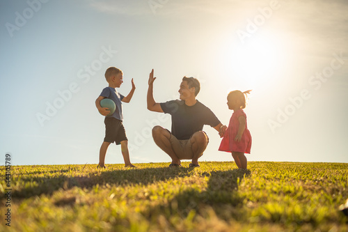 Father playing with his children having fun at the park. Parenting and raising children concept. 