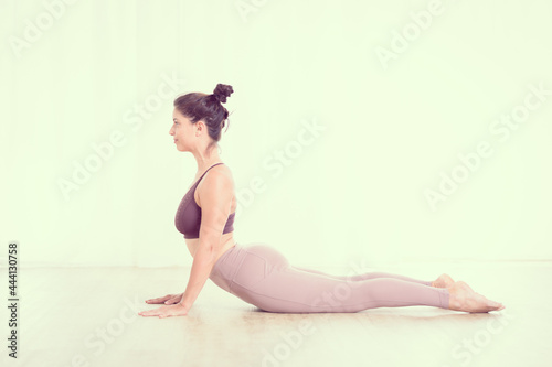 Portrait of gorgeous active sporty young woman practicing yoga in studio. Beautiful girl practice Sasangasana, rabbit yoga pose. Healthy active lifestyle, working out indoors in gym