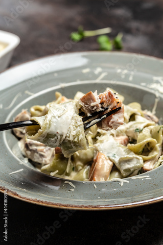 Traditional Italian cuisine, Tagiatelle pasta with creamy sauce with porcini mushrooms and chicken. cooking concept, vertical image. copy space