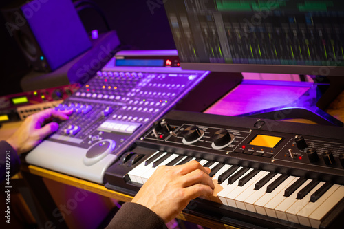 music producer, arranger, DJ hands remixing music on synthesizer keyboard, control surface and computer in home recording studio