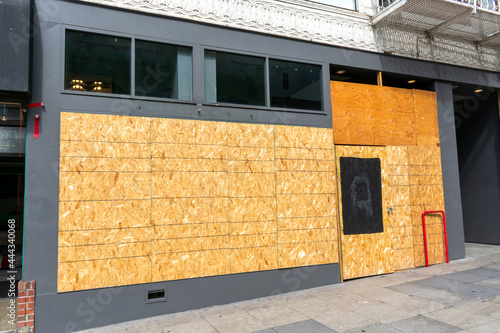 Exterior view of permanently closed business, store, restaurant boarded up with plywood sheets to prevent unauthorized access by squatters, looters or vandals to unused, vacant, or abandoned property