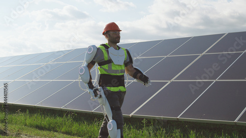 Male engineer in exoskeleton walking on solar plant