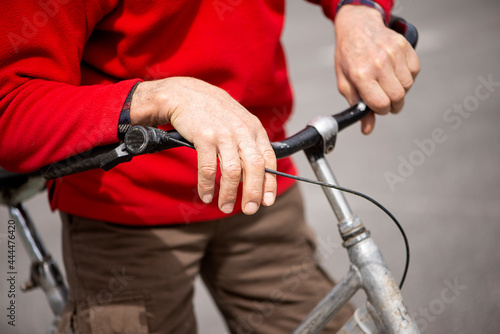 senior man's hands on the handlebars of an ancient bicycle