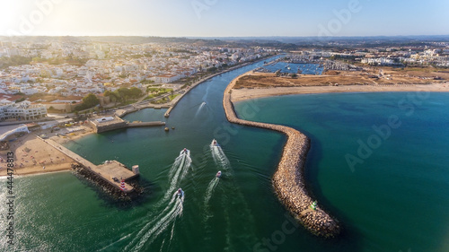 Aerial view from the sky of the Portuguese coastline of the Algarve zone of Lagos city. Boats and ships are moving in the direction of the port.