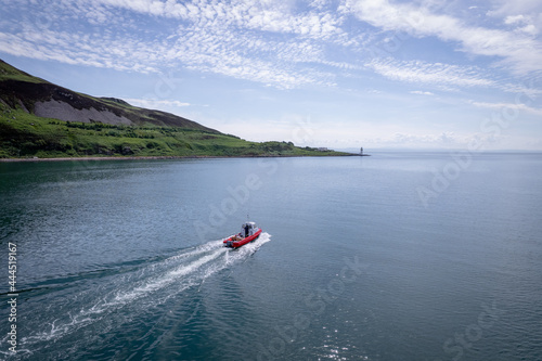 A Red Passenger Ferry Motors Alongside a Beautiful Coastline