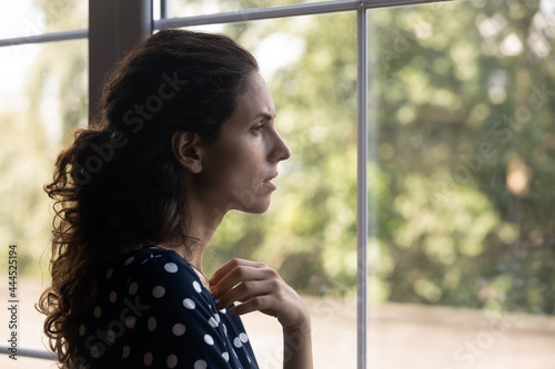 Frustrated depressed millennial woman looking out window, thinking over bad news, loss, disease, trying to cope with stress, despair, anxiety, grief. Crisis, depression, mental health disorder concept