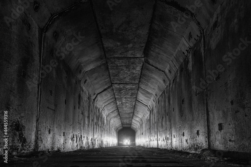 Empty abandoned railway dark tunnel with light in the end.