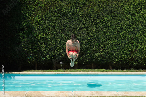 Young man jumping into a swimming pool. Summer concept.