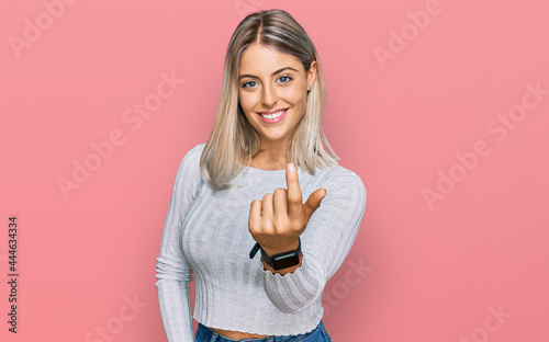 Beautiful blonde woman wearing casual clothes beckoning come here gesture with hand inviting welcoming happy and smiling