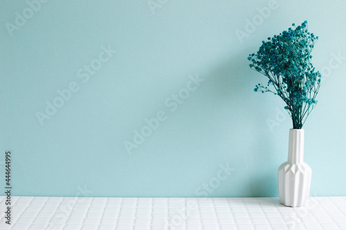 Vase of baby's breath, gypsophila dry flowers on white mosaic tile table. blue wall background. Home interior