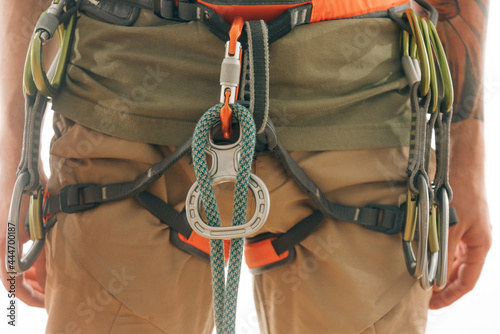 Close-up on a special 'Eight' device for belaying. Various climbing equipment hangs on the harness.