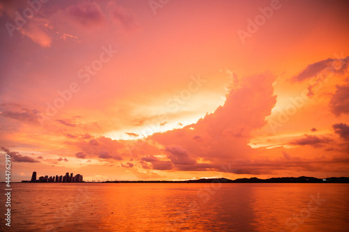 A fiery sunset illuminating the clouds with manmade construction on the horizon