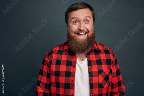 Waist-up shot charming smiling attractive guy with beard, wear red checkered shirt, laughing carefree having small talk in cafe with cute girl, talking friends at party joyfully, grey background