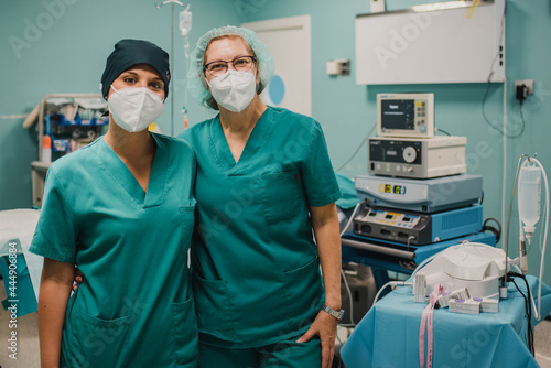 Portrait of medical nurses looking at camera inside operating theater at private clinic - Focus on right doctor face