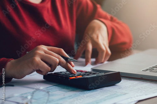 Close up businesswoman using calculator for doing math finance on wooden desk in the office. account, taxes, home budget concept