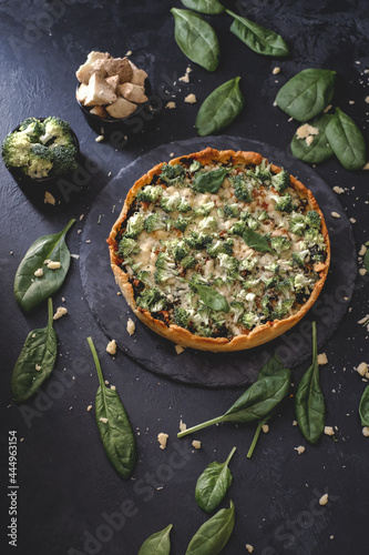 Millet quiche with spinach, salmon, broccoli and ricotta on dark wooden table. Homemade vegetarian cake. Copy space for text. Fresh pie with soft cheese. Healthy food. French cuisine
